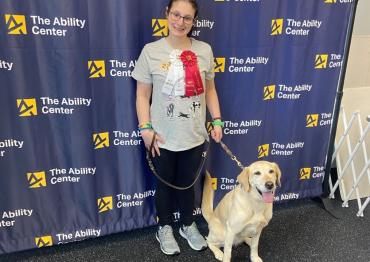Chloe at an event for The Ability Center in front of a step and repeat with a dog
