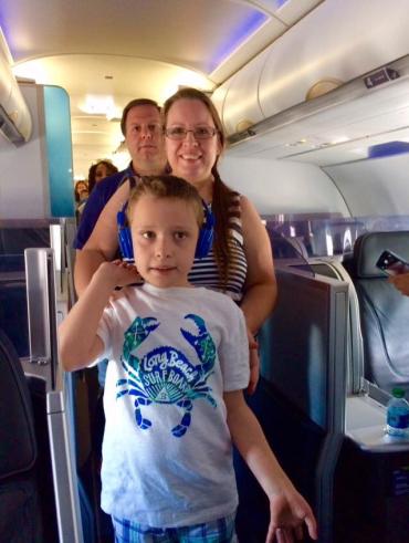 autistic child wearing headphones while traveling on a plane with his family