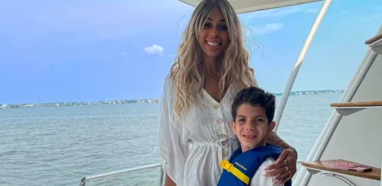a mother wearing a white dress and her son wearing a life jacket on a boat