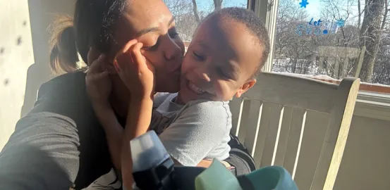 a mother kissing her young son on the cheek as he smiles
