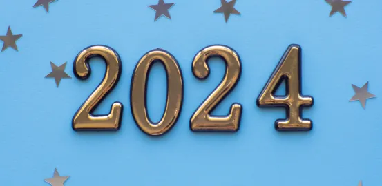 gold 2024 letters against light blue background with small metallic stars scattered in background