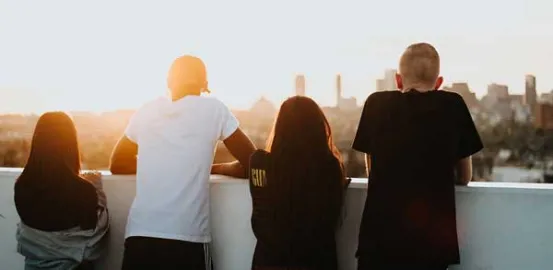 4 teens on a rooftop overlooking a city at sunset