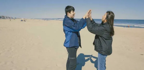 a mother and son high fiving on the beach