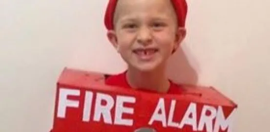 An autistic boy wearing a Halloween costume of a fire alarm