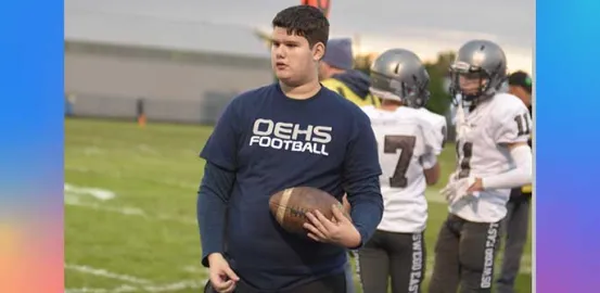 Andrew holding a football and wearing an OEHS football shirt