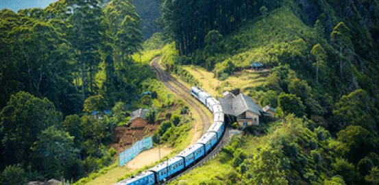 Blue train going down a mountain near houses