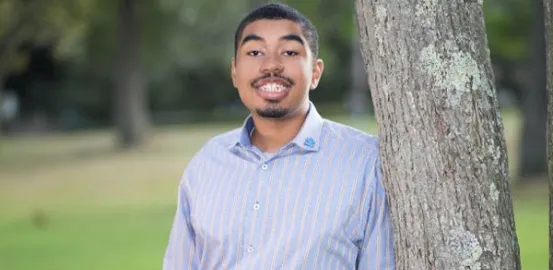 Chase smiling and leaning against a tree