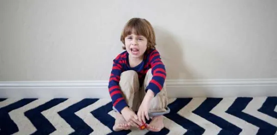 Chrissy Kelly's young son sitting against the wall with a sad face