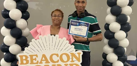 DJ and his mom holding a sign that says 'Beacon Bound'