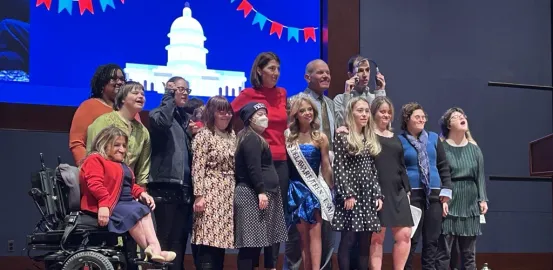 Group of 14 disability advocates standing together on stage