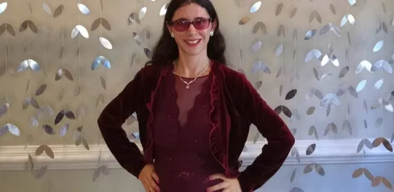 Kelly wearing a red dress in front of a silver backdrop