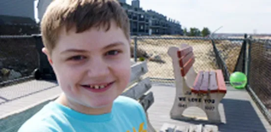 Kimberlee Rutan McCafferty's son sitting on a bench wearing a blue shirt 