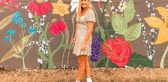 Mallory in front of a painted flower mural