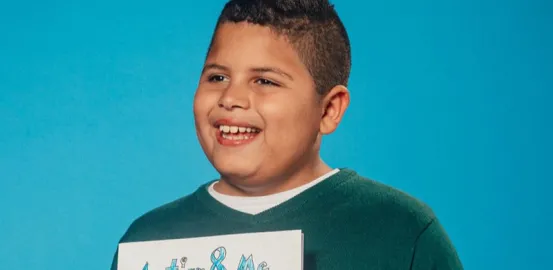 Milan holding up a book about autism and smiling