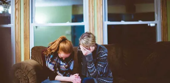 Sad people sitting on a couch comforting each other