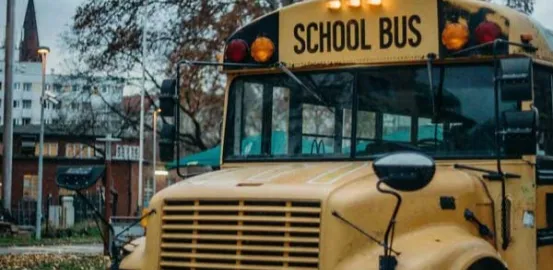 School bus in front of a school in autumn