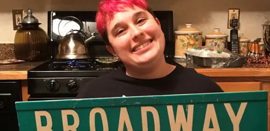 Sophie holding a Broadway street sign