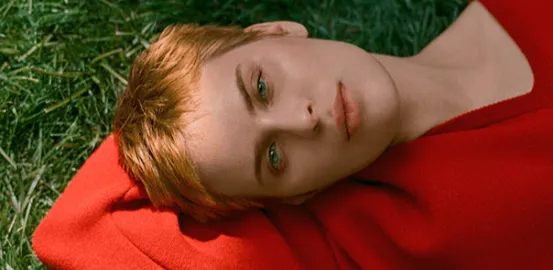 Tallulah Willis laying in the grass wearing a red sweater