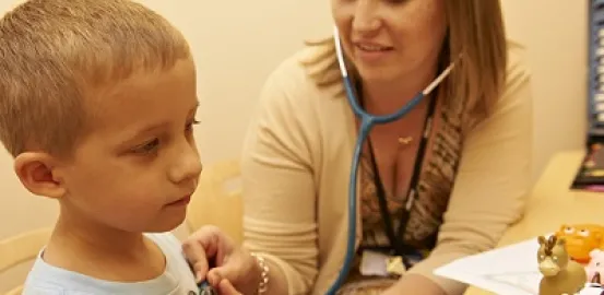 doctor using a stethoscope on a young blonde boy