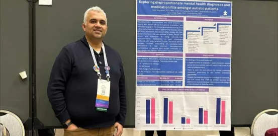 Vijay Vasudevan standing in front of a poster with his research