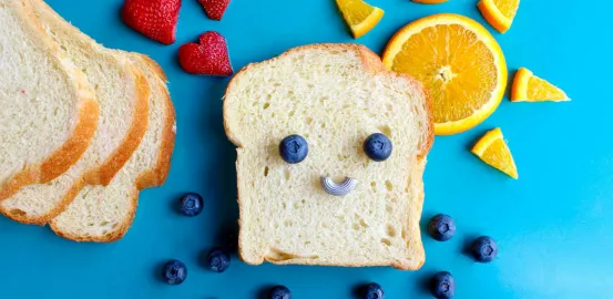 a piece of bread with fruit on top to make a smiley face