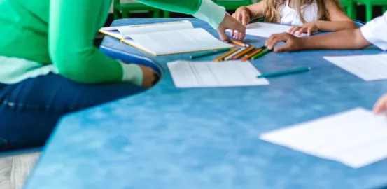 a teacher sitting around a blue table with students