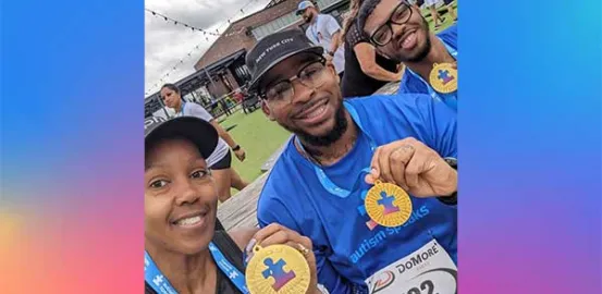 a family of 3 holding up Autism Speaks medals after an endurance event