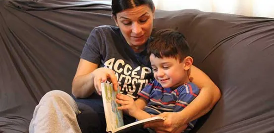 a mother reading her son a book on the couch