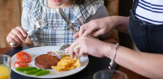 a mother teaching her daughter table manners