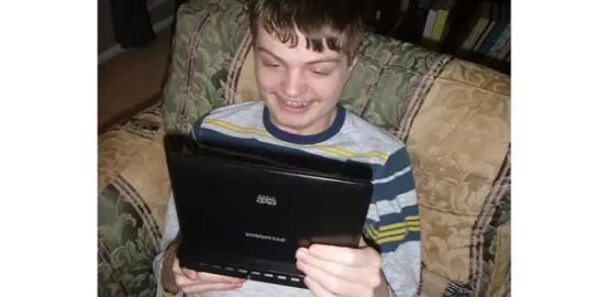 autistic child looking at an iPad and smiling