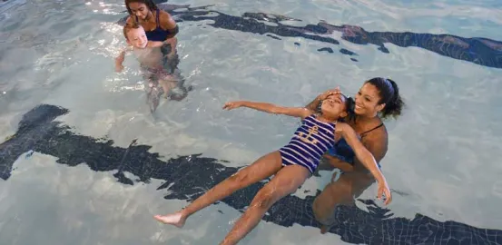 child floating in the pool with an adult during a swimming lesson