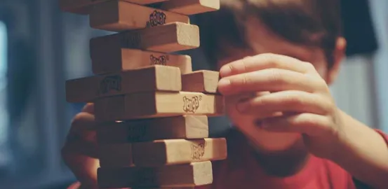 child in a red shirt playing Jenga