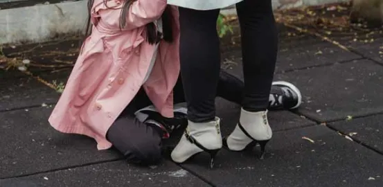 child in pink jacket sitting on the ground next to mother