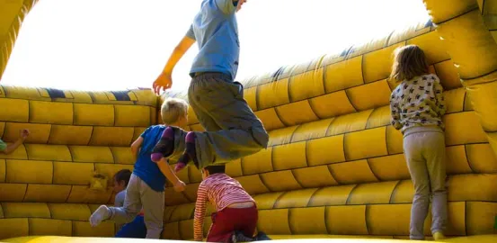 children jumping in a bounce house at a party