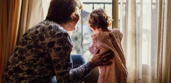 grandmother looking out the window with her granddaughter