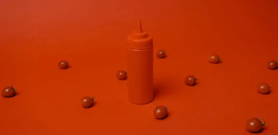 ketchup bottle on a red table with tomatoes