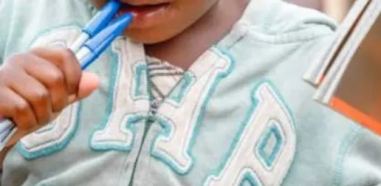 little boy chewing on pens