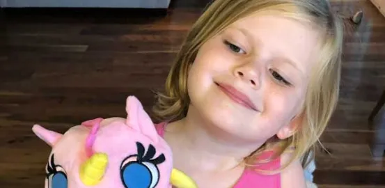 little girl holding a pink stuffed unicorn