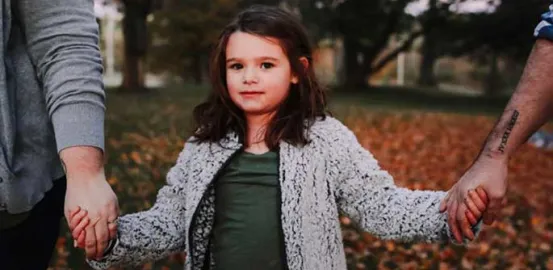 little girl holding her parents hands