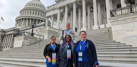 one male and three female advocates standing on the steps of the US Capitol with building dome in the background