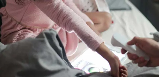 parent taking their child's temperature on the wrist with a heat thermometer