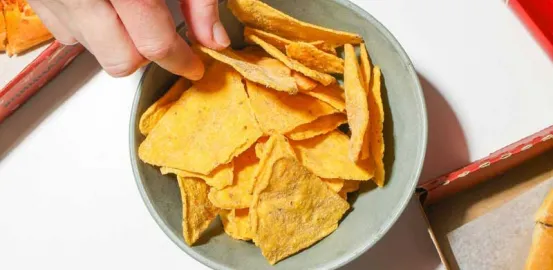 person with their hand in a bowl of chips