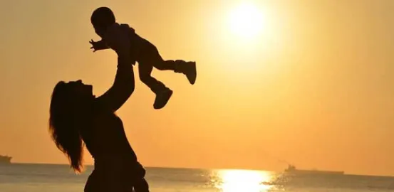 silhouette of a mom holding her child in the air