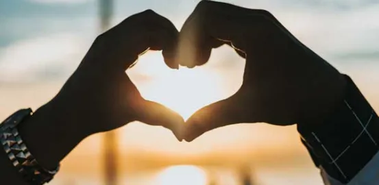 two people putting their hands together to make a heart shape