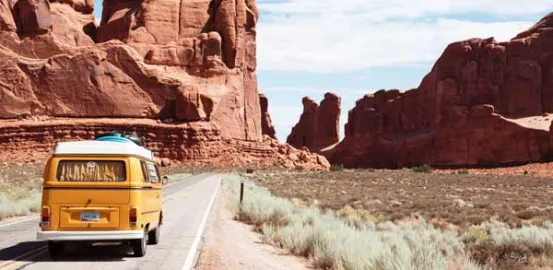 yellow camper van driving through mountains