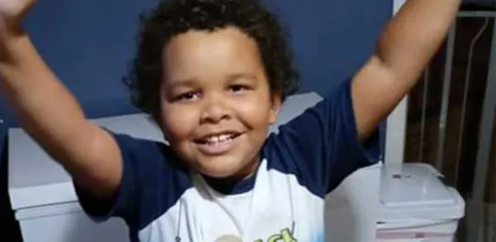 young boy smiling with his arms raised