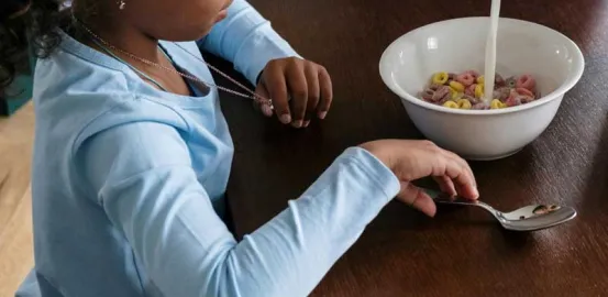 young girl eating cereal at the table