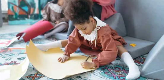 young girl holding a pencil and writing on yellow paper