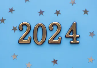 gold 2024 letters against light blue background with small metallic stars scattered in background