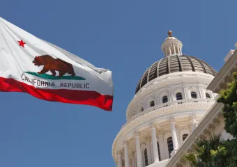 Photo of California state flag next to capitol dome